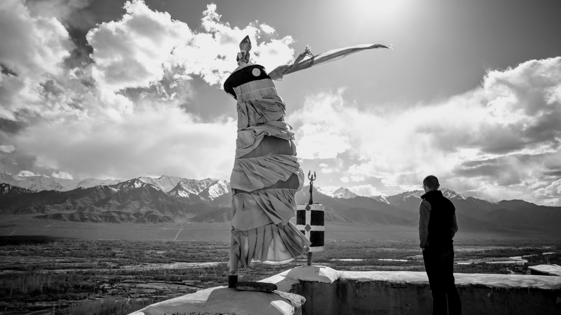 Drapeau de prière au vent face aux montagnes de l'Himalaya, voyageur en contemplation — noir et blanc