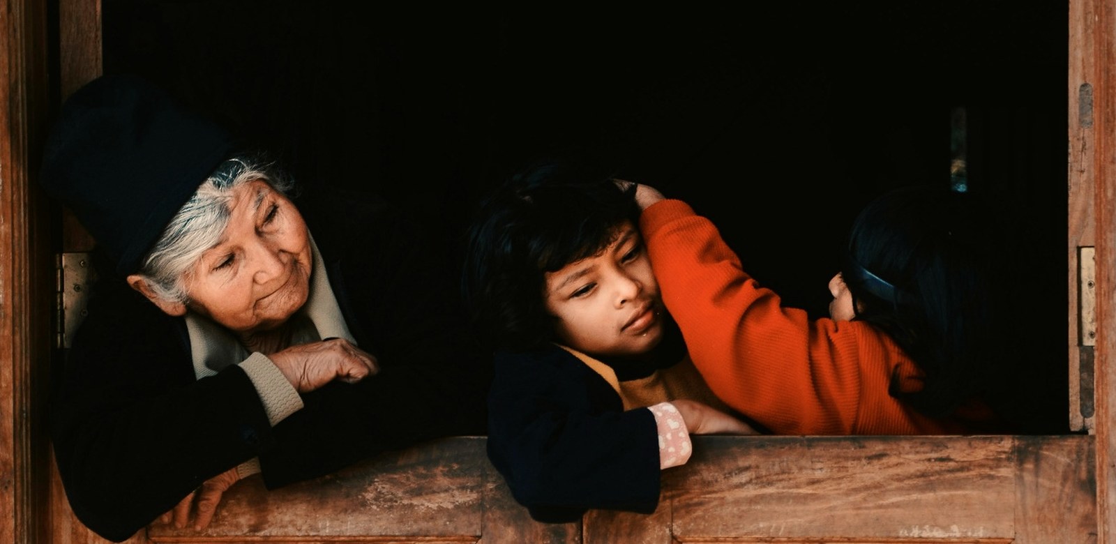 Une grand-mère et un enfant accoudés à une porte en bois en Amérique latine